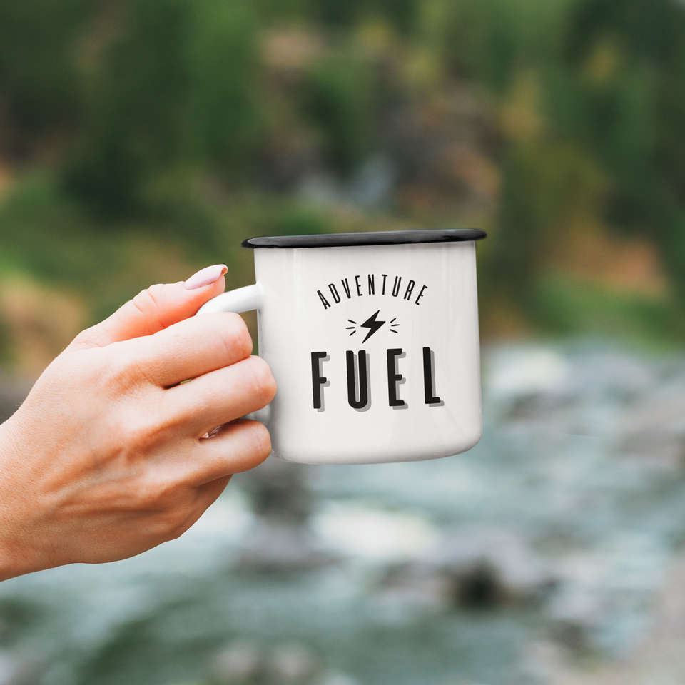 Hand holding enamel mug Adventure Fuel